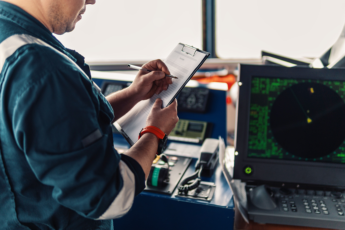 Marine navigational officer or chief mate on navigation watch on ship or vessel. He fills up checklist. Ship routine paperwork; Shutterstock ID 1225757410; purchase_order: -; job: -; client: -; other: -